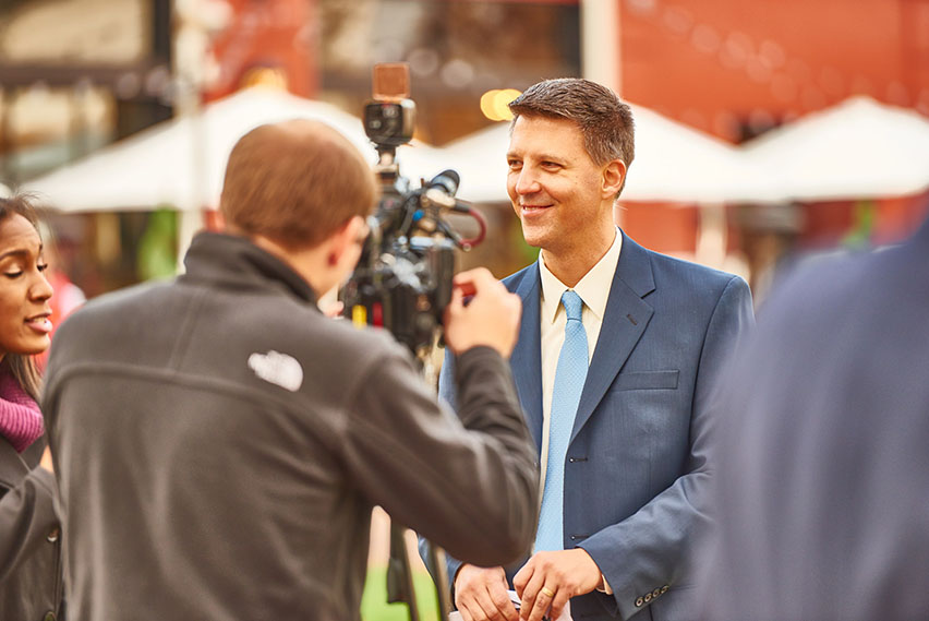 Kevin Cedik smiling in front of a TV camera
