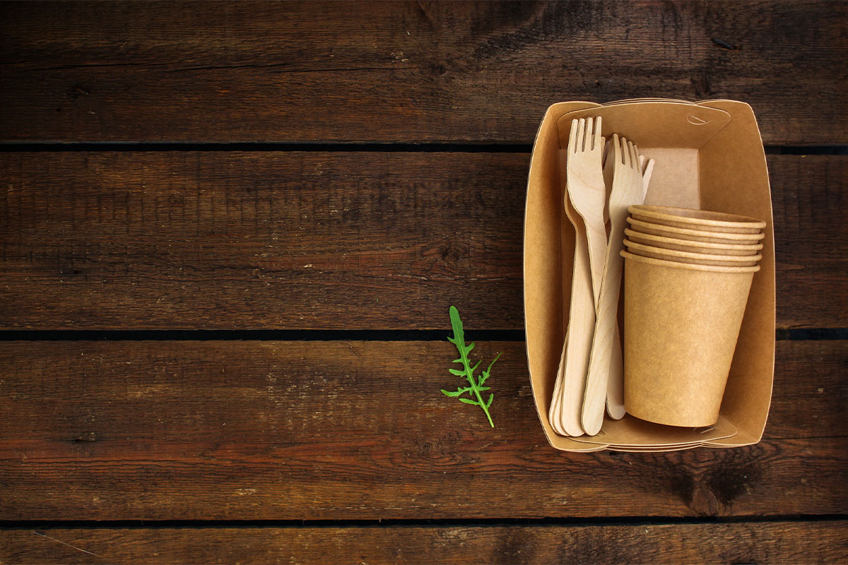 Paper cups and wooden spoons in paper bowls on a wooden tabletop