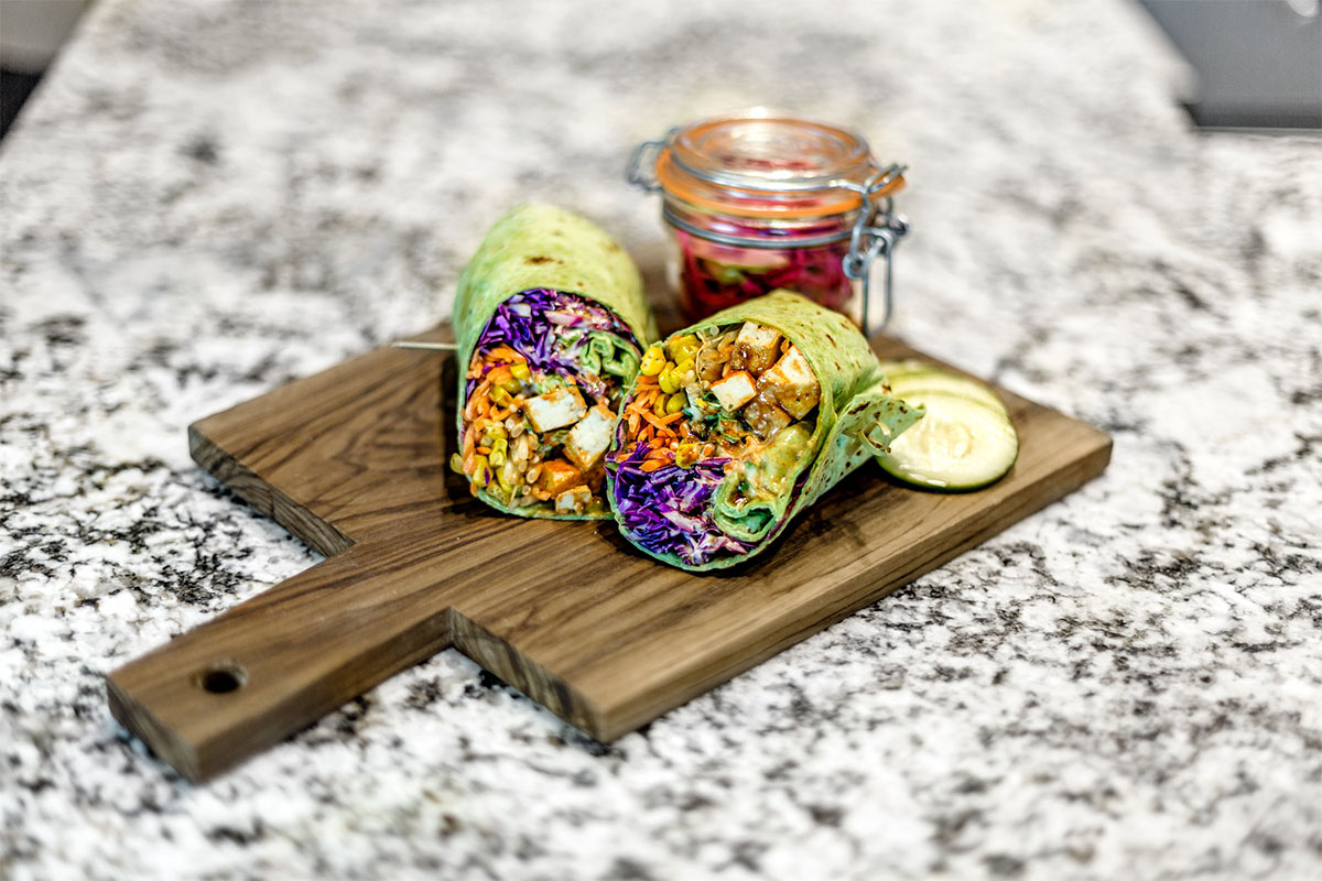 A mediterranean spinach wrap on a wooden cutting board