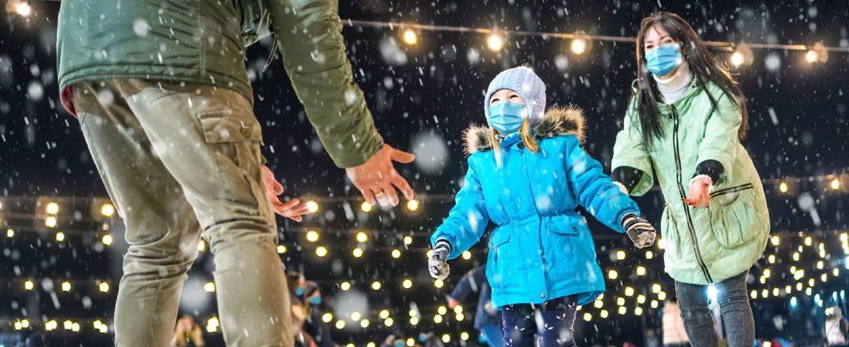 A young girl playing in the snow with her parents