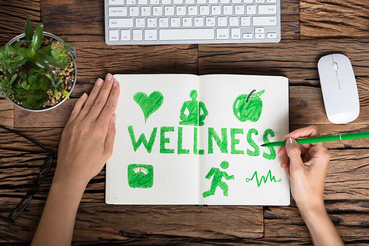 "Wellness" written in green marker in a notebook on a desk