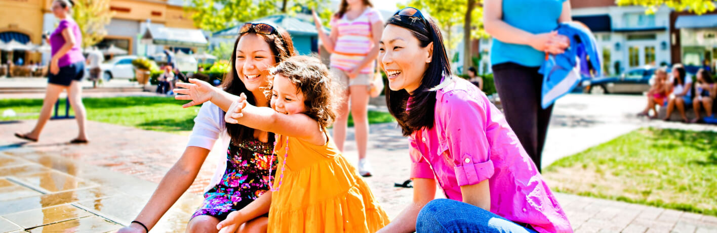 Woman in a pink shirt smiling with a young girl in a yellow dress