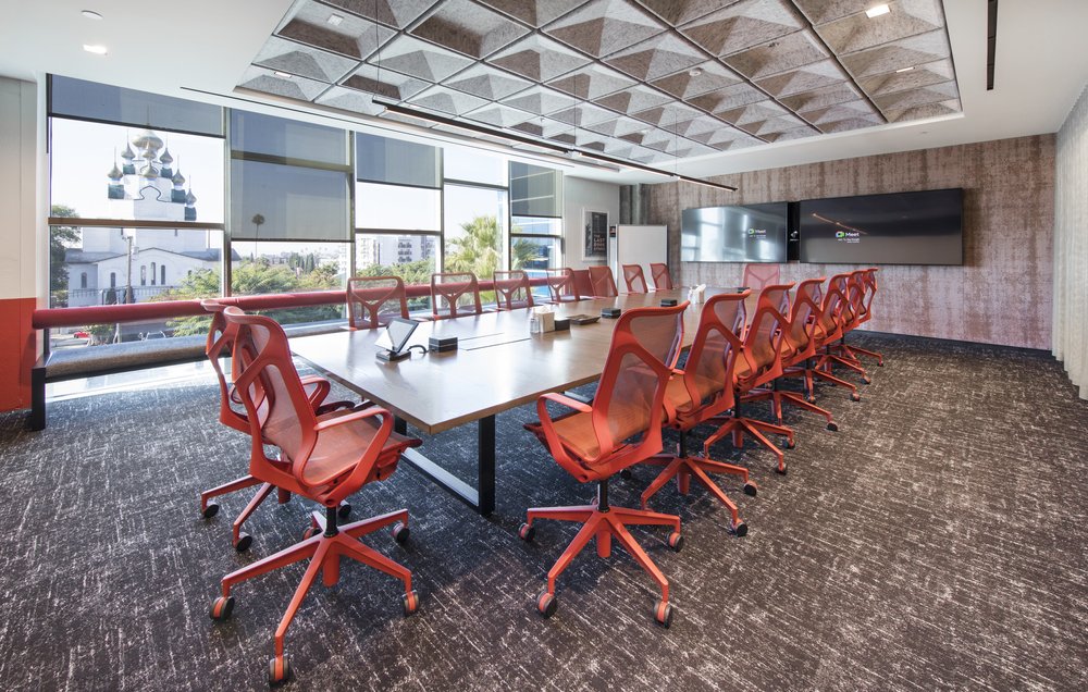 Conference room with red chairs around a long wooden table